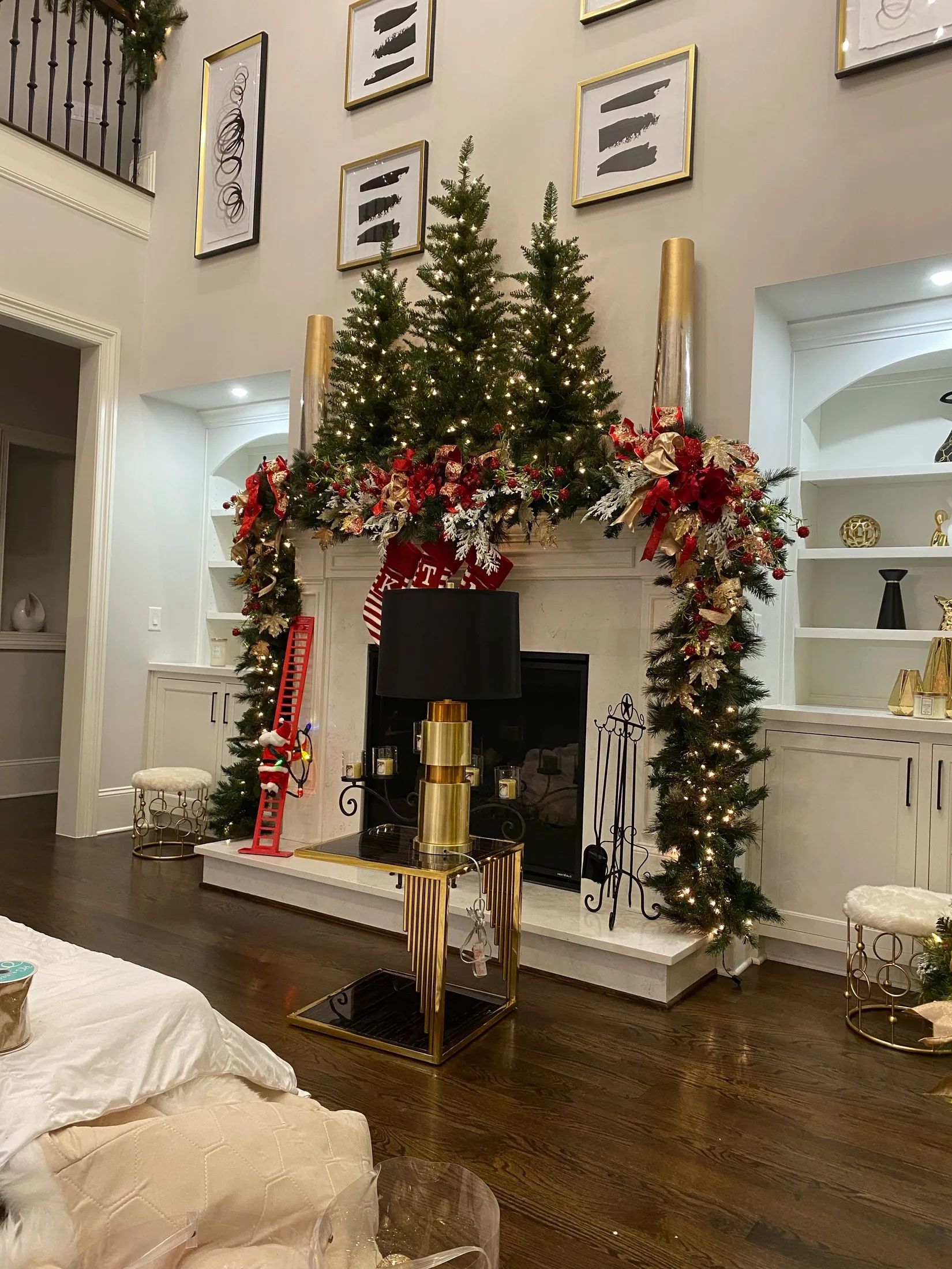 A real formal fireplace mantel decorated with red and gold Christmas garland and a tree