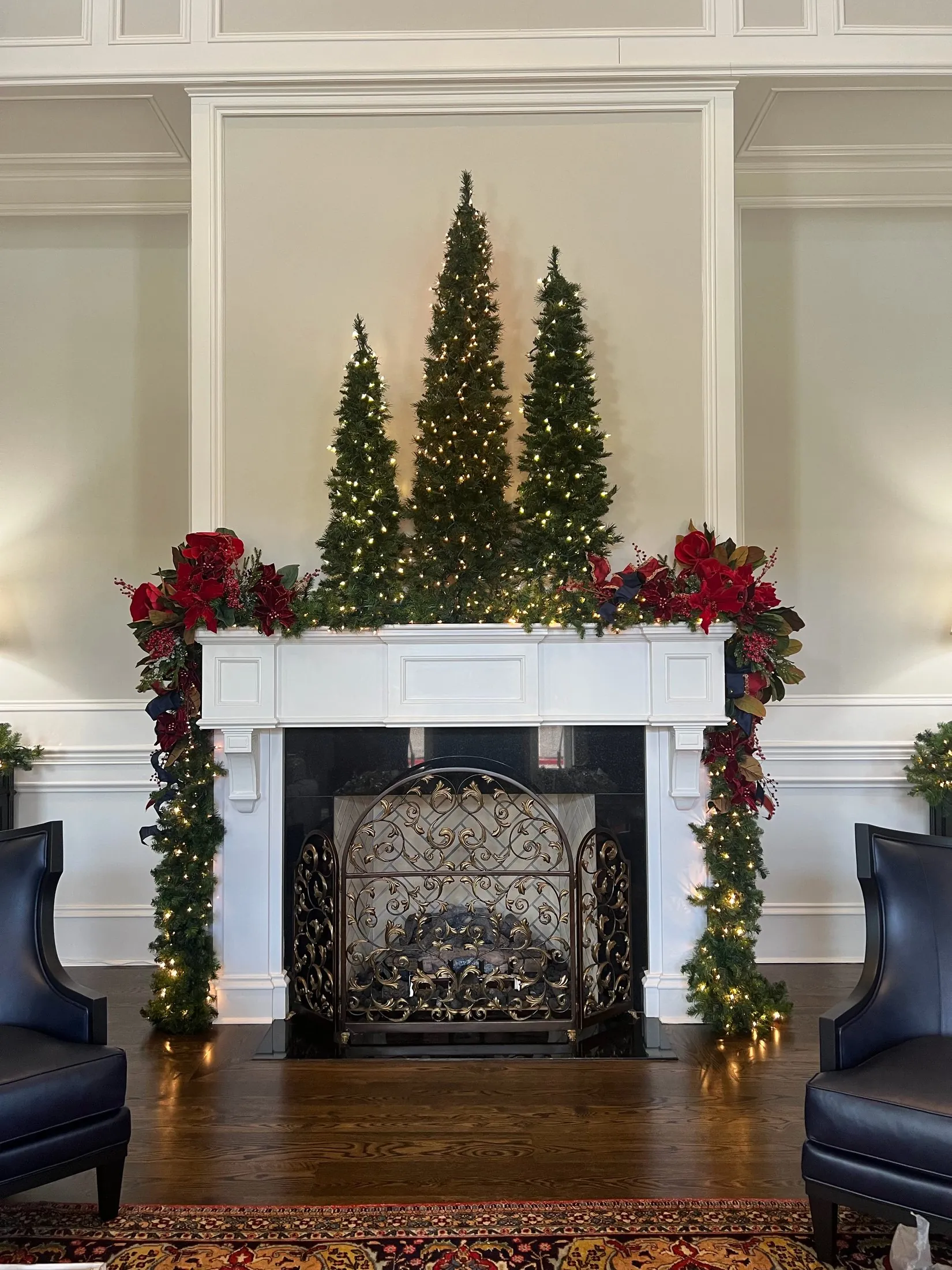A real formal fireplace mantel with greenery and red Christmas decorations