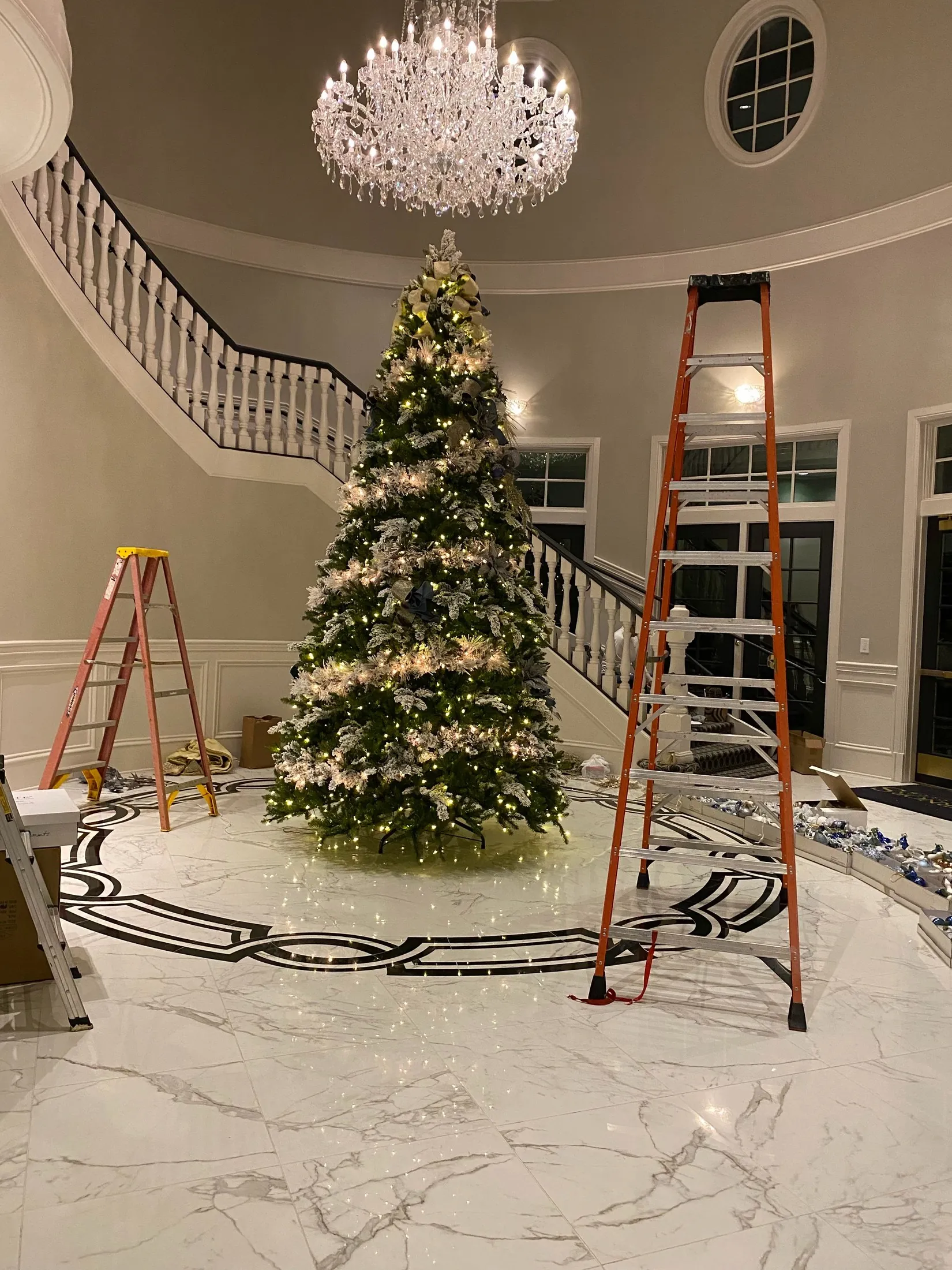 A real grand foyer Christmas tree installation with tall ladders during styling