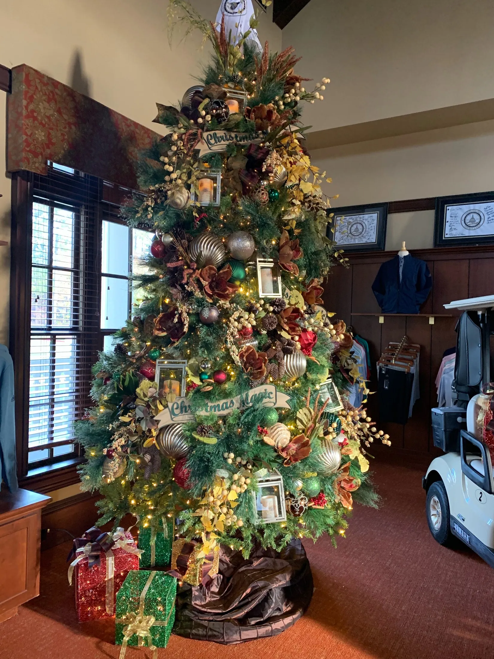 A real Christmas tree with green, gold, and red decorations in a club setting