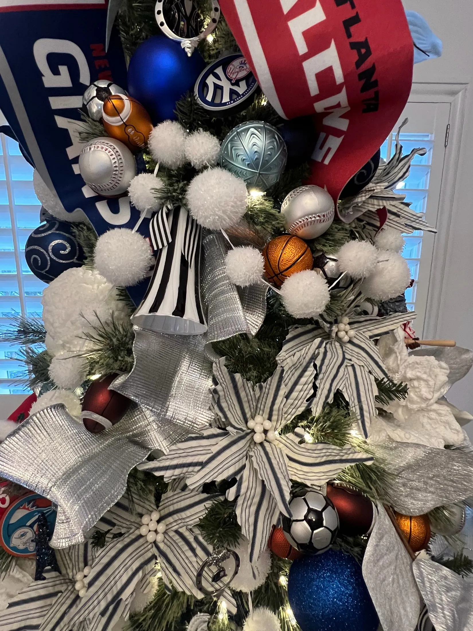 Close-up of real sports-themed ornaments, ribbon, and textured Christmas tree details